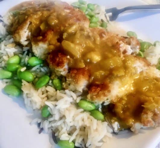 A plated dish of a breadcrumbed chicken breast fillet serve on a bed of rice with Katsu Sauce over the chicken 