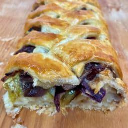 A baked Cheese and Onion Plait, slice through showing the filling