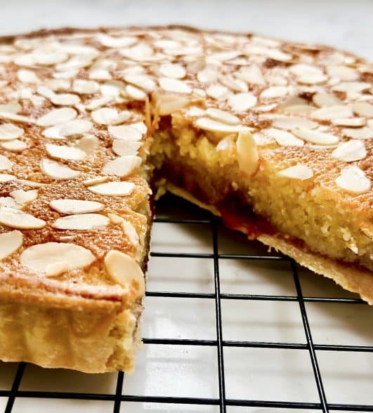 A baked Bakewell Tart with a slice cut out