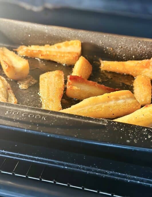 Tray of honey roasted parsnips cooking in the oven 