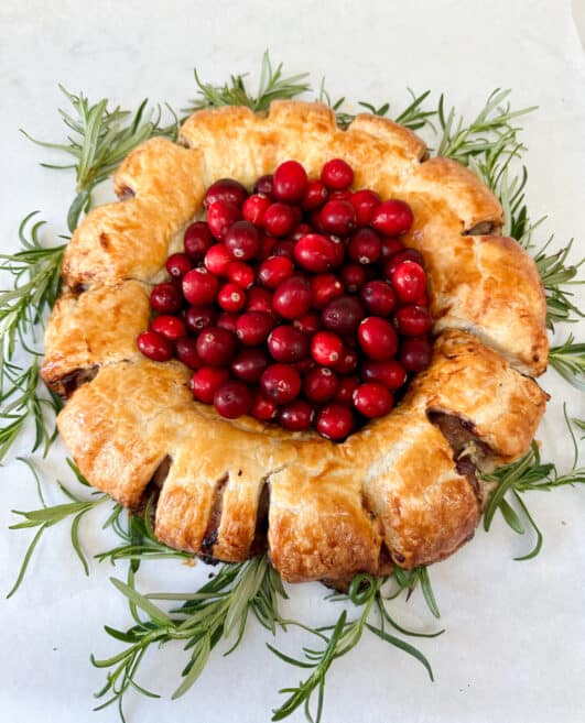 sausage roll in a treat decorated with cranberries and rosemary